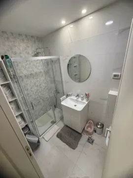 Svijetlo moderno kupatilo sa tuš kabinom, umivaonikom i okruglim ogledalom. - image 7
