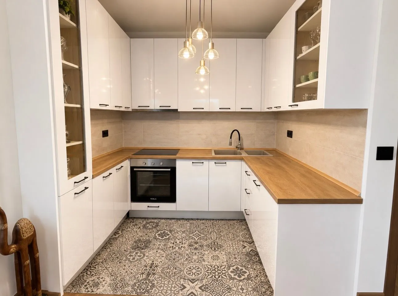 Modern kitchen with white cabinets and a wooden countertop.