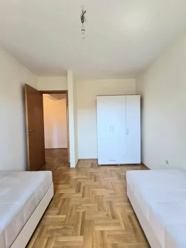 Spavaća soba sa dva kreveta i bijelim ormarom. - image 7