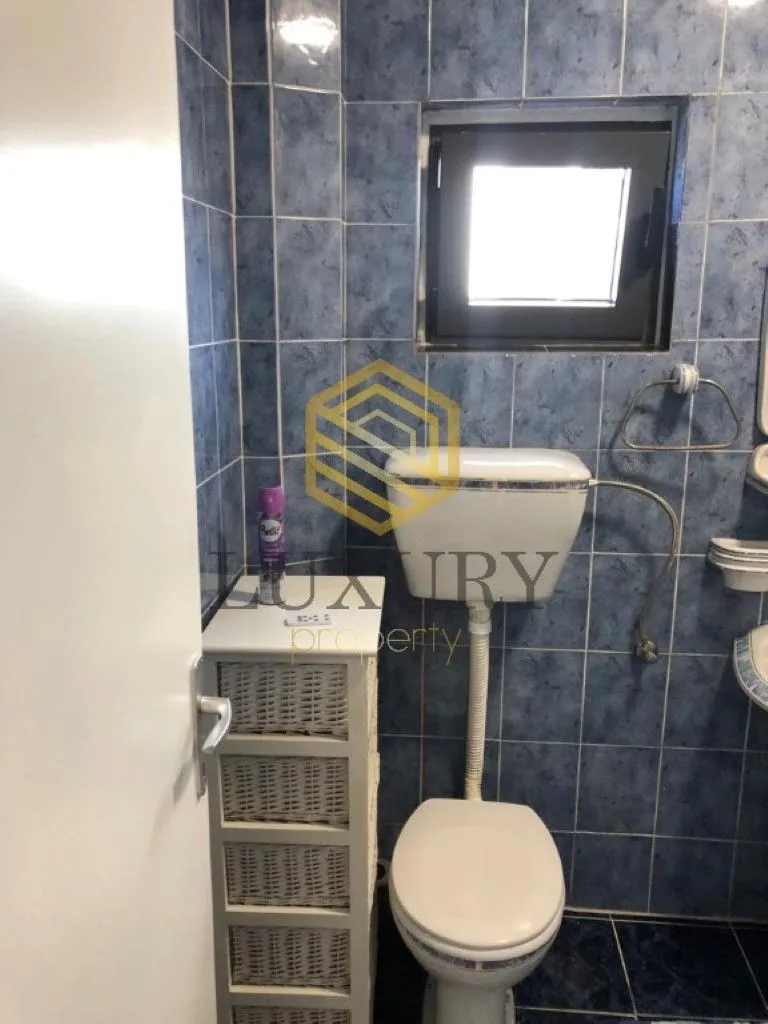 Manje kupatilo sa plavim zidnim pločicama i WC šoljom.