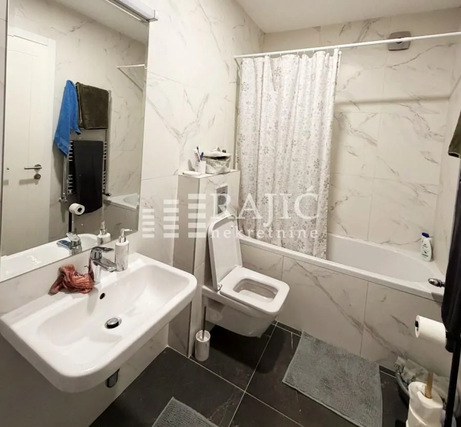 Modern bathroom with a sink, toilet, and bathtub.