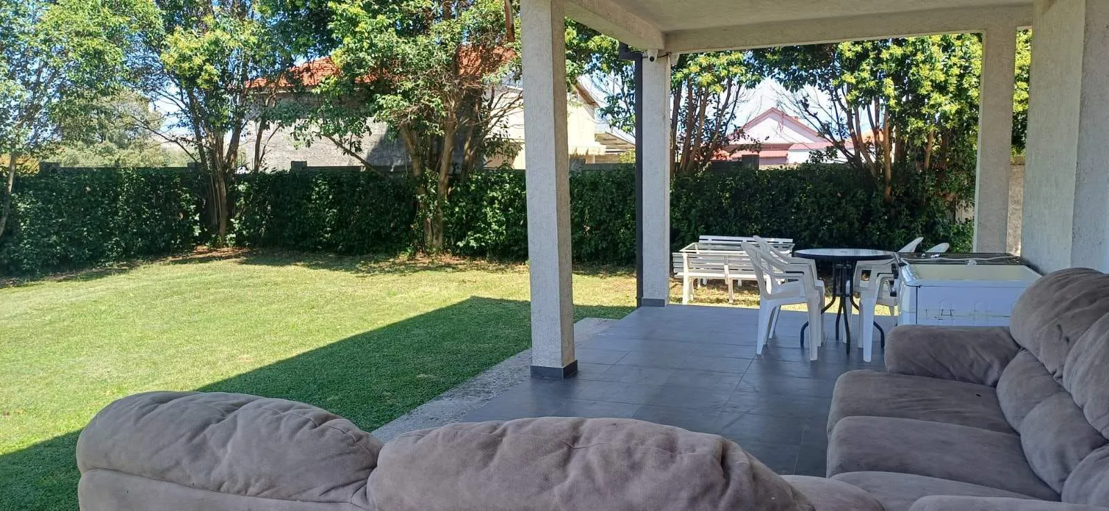 Covered terrace with seating furniture and a view of the yard.