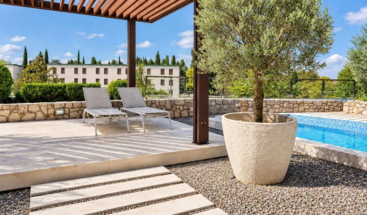 Terrace with a pergola, sun loungers, and a swimming pool.
