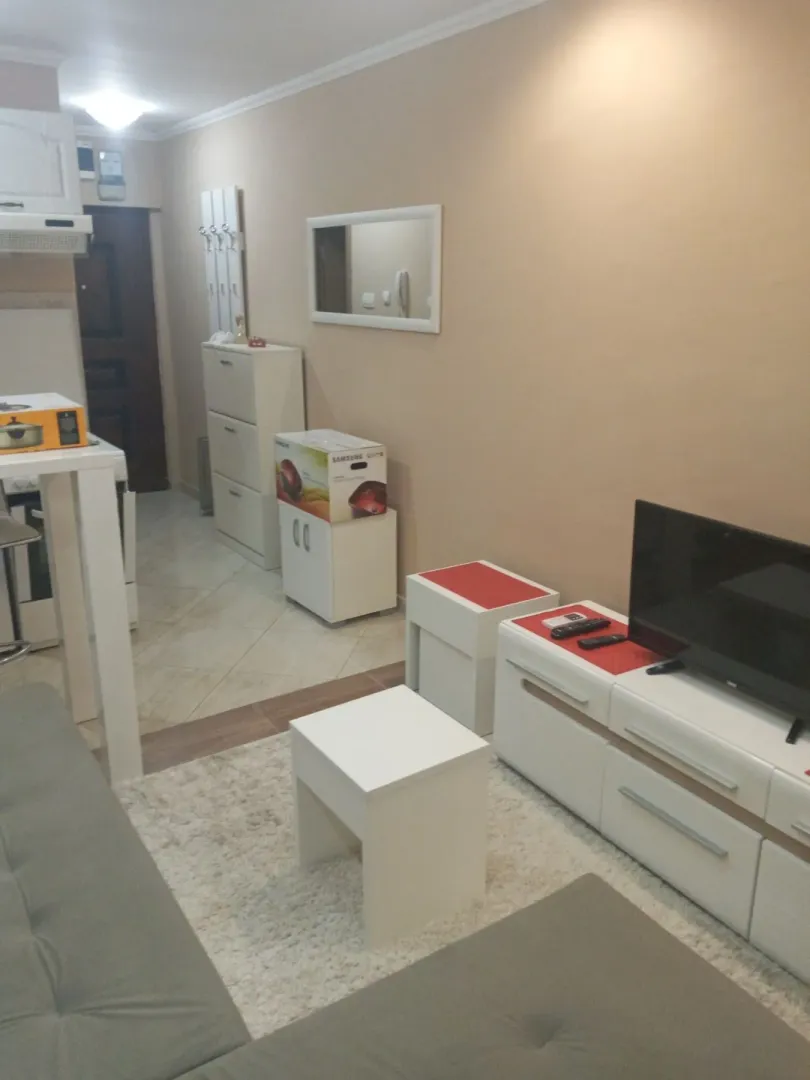Dnevna soba sa TV komodom i malim stolom.