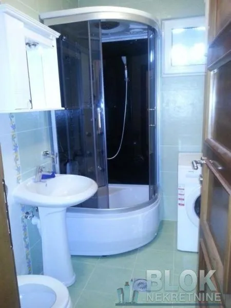 Bathroom equipped with a shower cabin, washbasin, and washing machine.