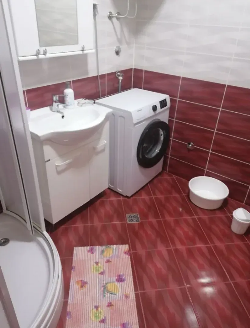 Kupatilo sa umivaonikom, veš mašinom i tuš kabinom.