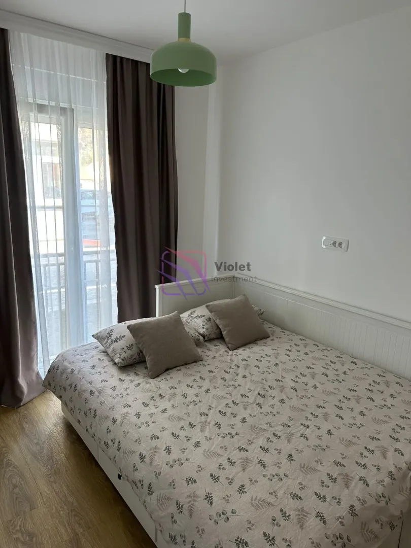 Manja spavaća soba sa bračnim krevetom i izlazom na balkon.