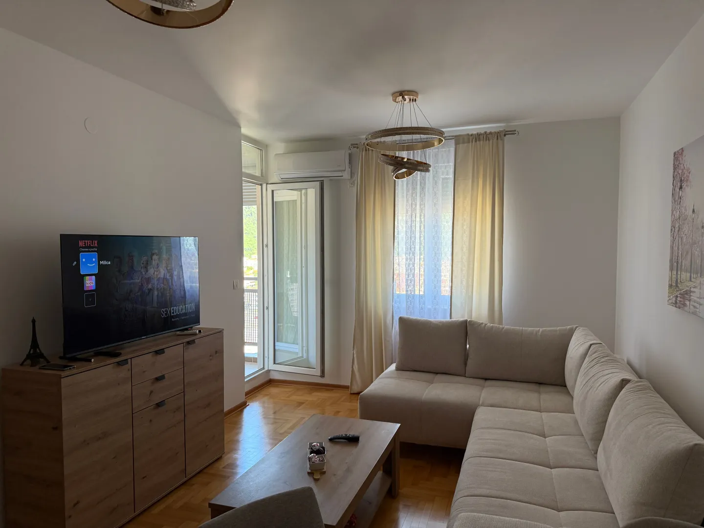 Bright living room with a sectional sofa, television, and access to the terrace.