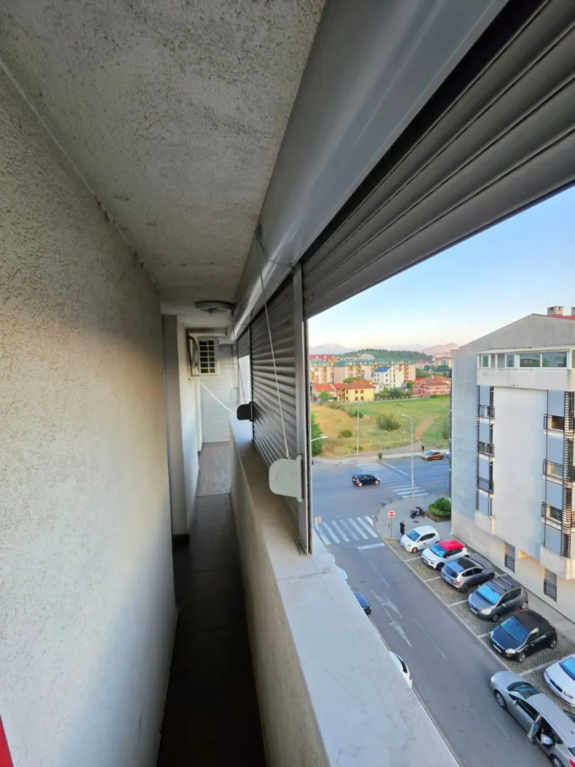 Pogled sa balkona na ulicu i okolne zgrade.