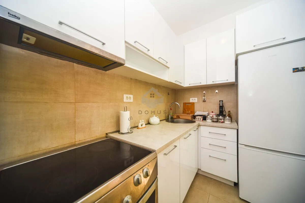 Compact white kitchen with built-in appliances and a stove.