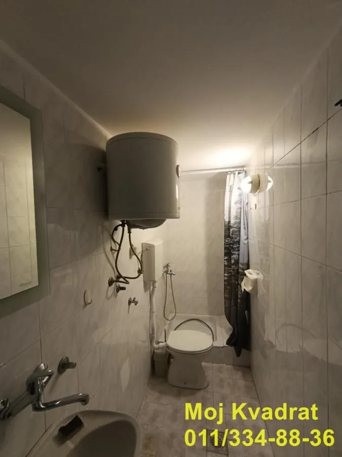 Smaller bathroom with a shower cabin and water heater.