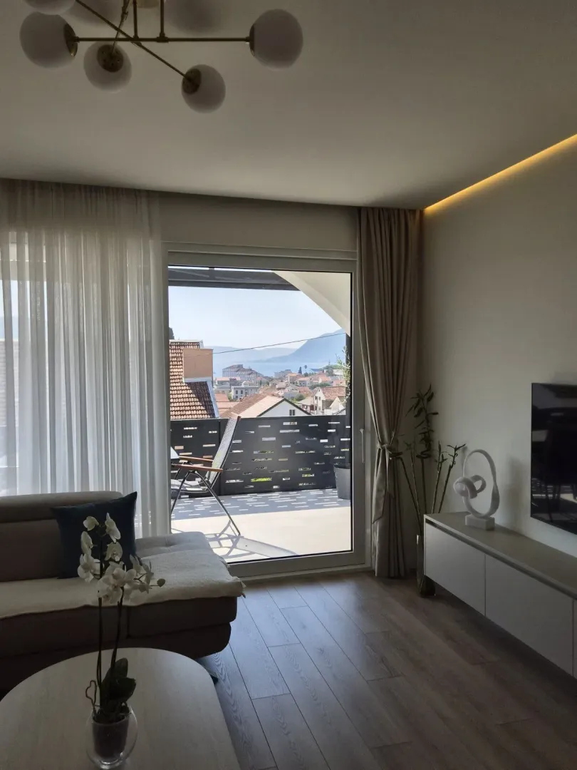 Dnevna soba sa garniturom, televizorom i izlazom na terasu sa pogledom.