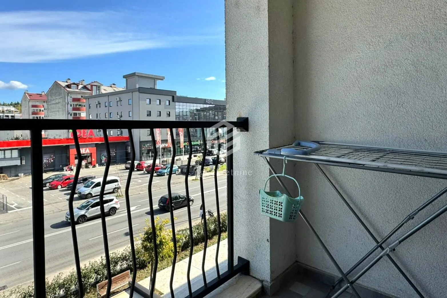 Balcony with a street view and a clothes drying rack.