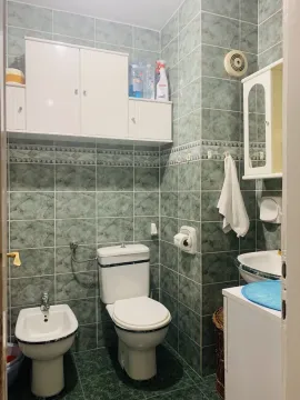A bathroom featuring green tiles, a toilet, and a bidet. - image 9
