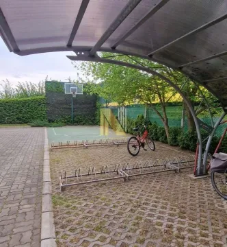 Covered bicycle parking in front of a sports court and yard. - image 8