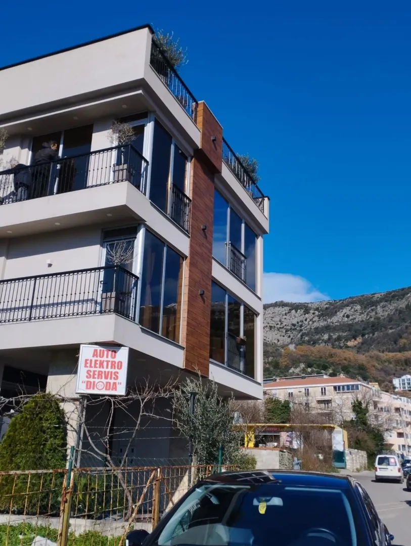 Pogled na spoljašnjost zgrade sa terasama i okolnim pejzažem.