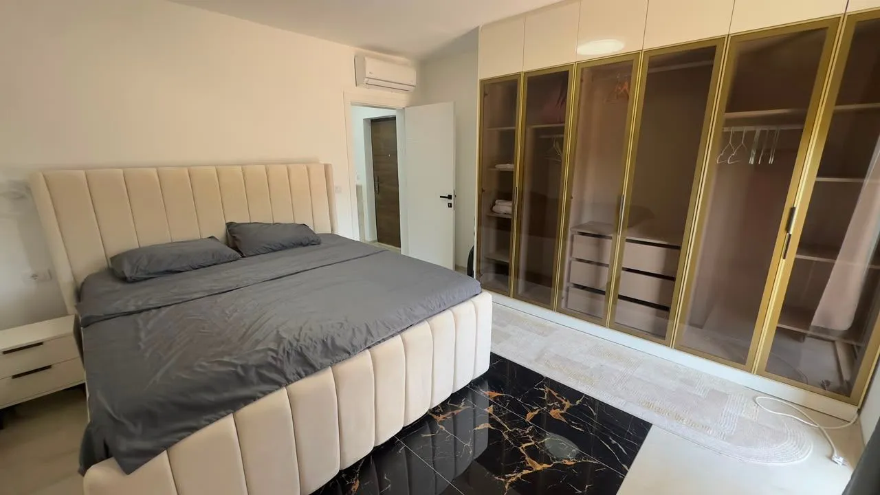 Moderna spavaća soba sa bračnim krevetom i velikim ugradnim plakarom.