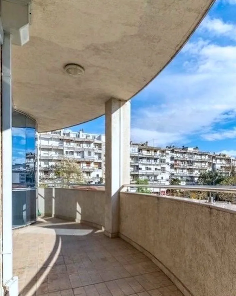 Prostrani natkriveni balkon sa pogledom na okolne zgrade i gradsku sredinu.