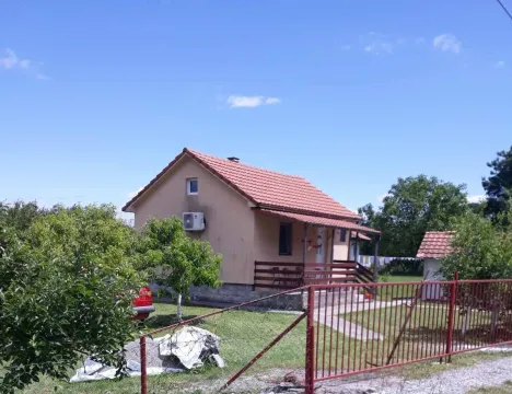 Spoljašnji izgled manje prizemne kuće sa uređenim dvorištem i ogradom. - image 3