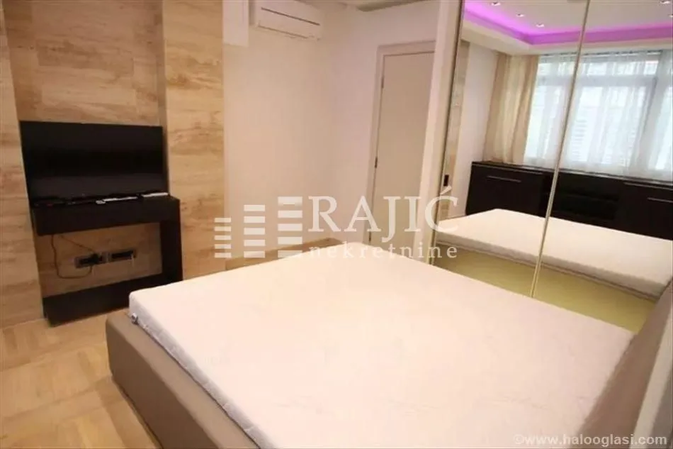 Furnished bedroom with a double bed, wardrobe, and TV.