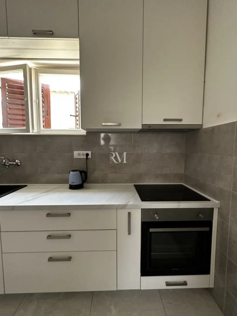Modern kitchen with white cabinets and a built-in oven.