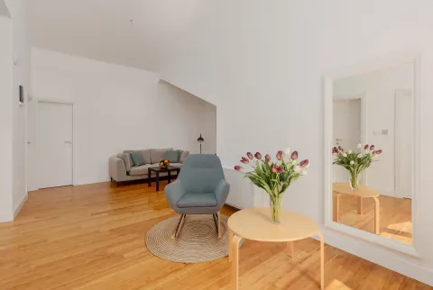 Living room with a sofa, an armchair, and wooden flooring. - image 12