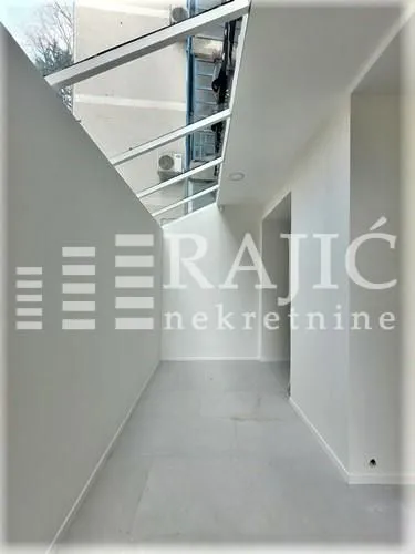 Enclosed space with a glass roof and white walls.
