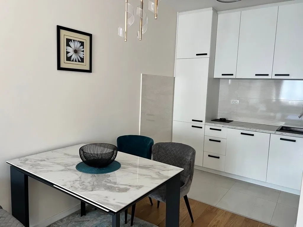 Modern kitchen with white units and a dining table.