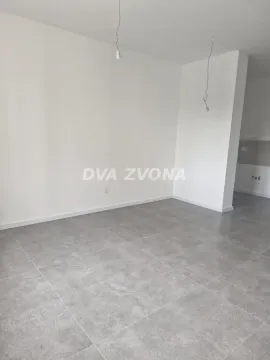 Prazna neopremljena prostorija sa sivim pločicama na podu i belim zidovima. - image 3