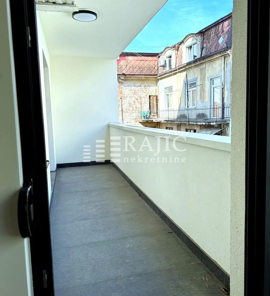 Dugačka terasa sa pogledom na susedne zgrade.