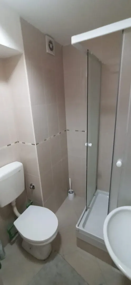 Manje kupatilo sa tuš kabinom, wc šoljom i umivaonikom.