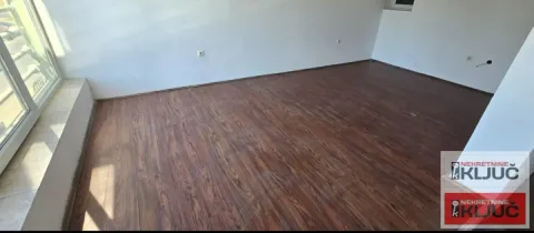 Empty room with dark laminate flooring and a large window. - image 14