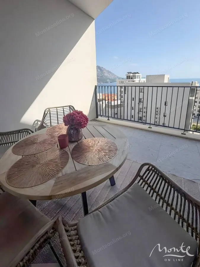 Namješten balkon sa stolom, stolicama i pogledom na more i okolinu.
