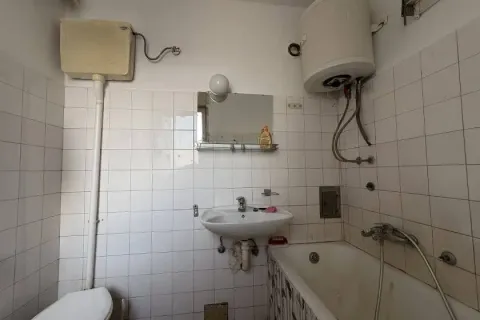 Starije kupatilo sa kadom, umivaonikom i wc šoljom obloženo belim pločicama. - image 2