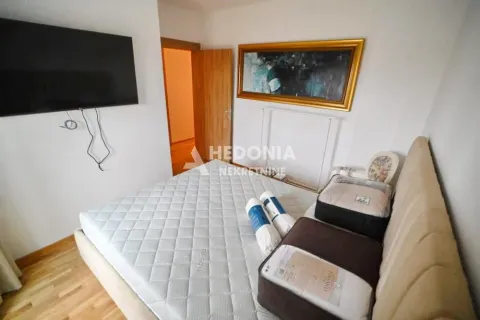 Spavaća soba sa bračnim krevetom, televizorom na zidu i umetničkom slikom. - image 12