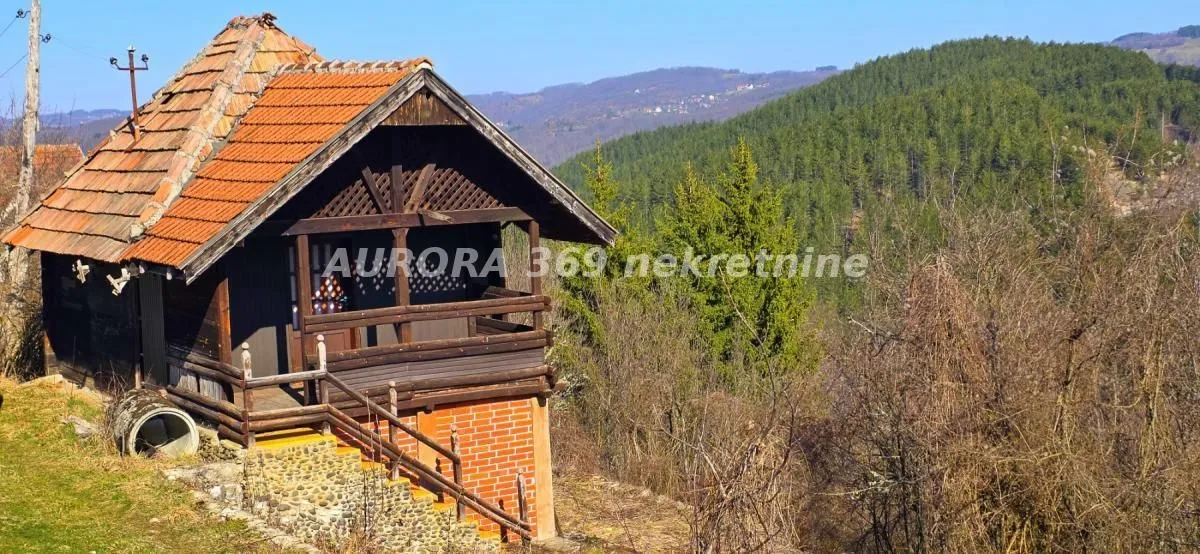 Pogled na seosku kuću sa drvenom fasadom i krovom od crepa u prirodi.
