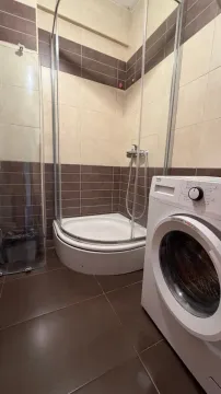 Bathroom with a shower cabin and a washing machine. - image 5