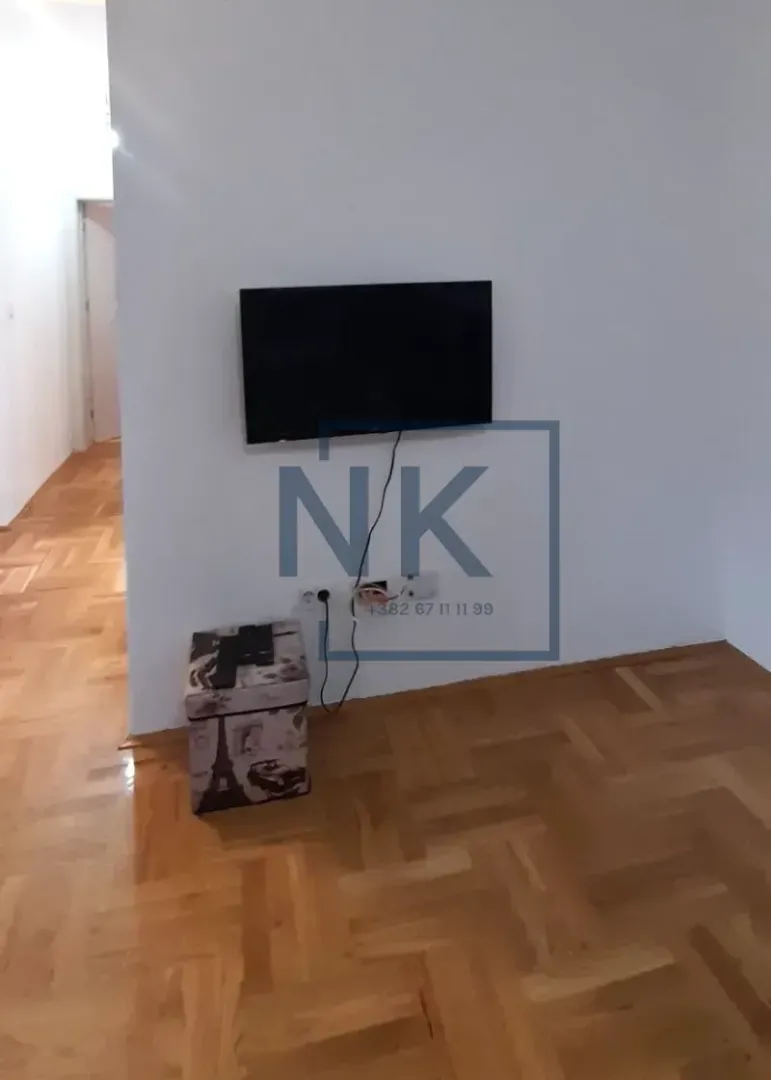 Pogled na zid sa televizorom i drvenim parketom.