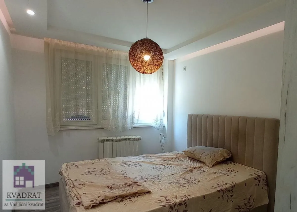 Nameštena spavaća soba sa bračnim krevetom i prozorom.