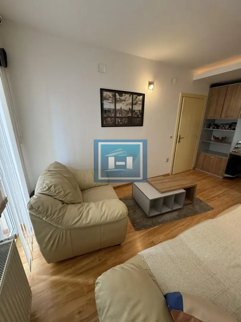 Smaller living room with an armchair, coffee table, and shelving unit.