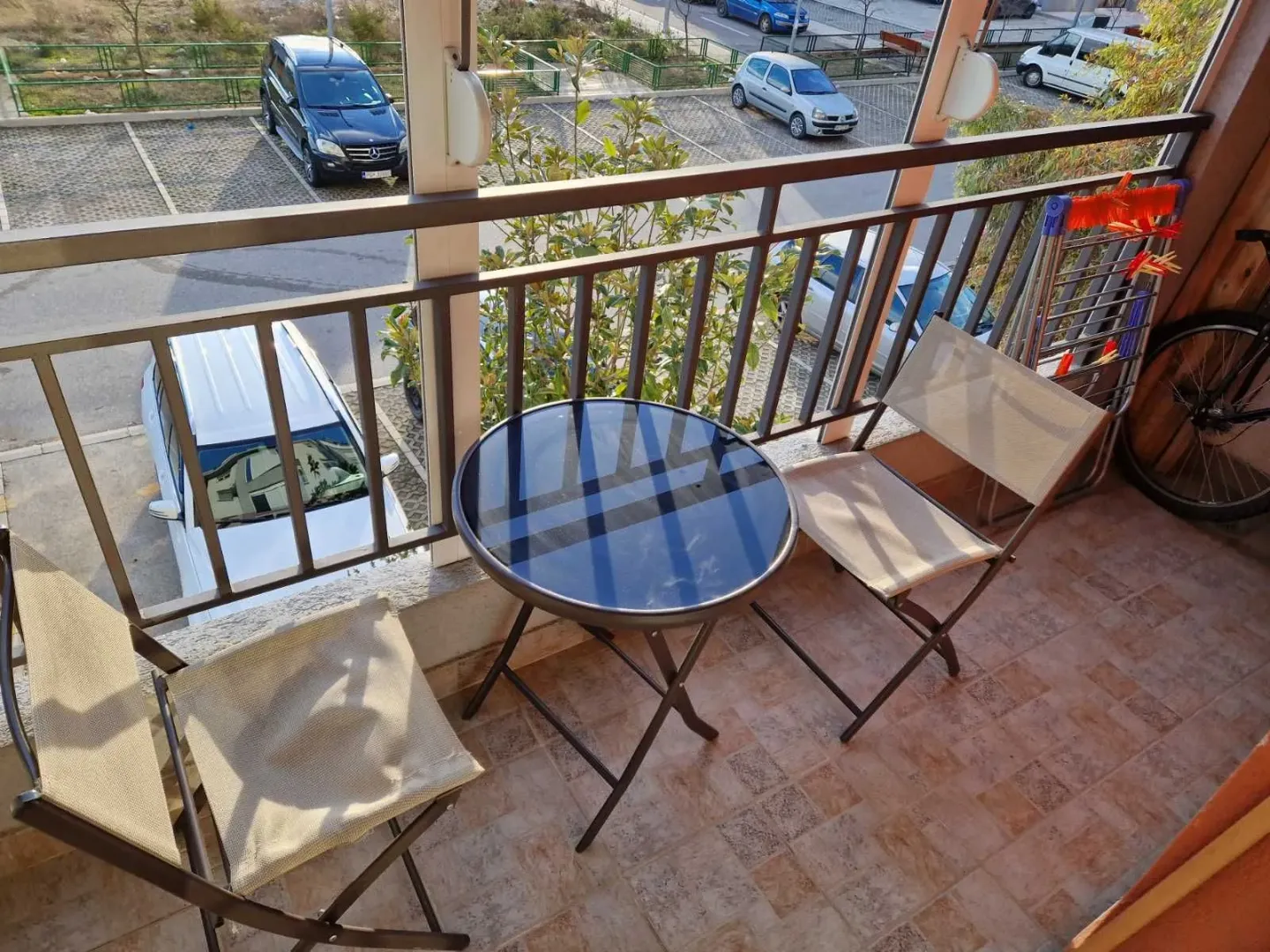 Namješten balkon sa stolom i dvije stolice i pogledom na parking.