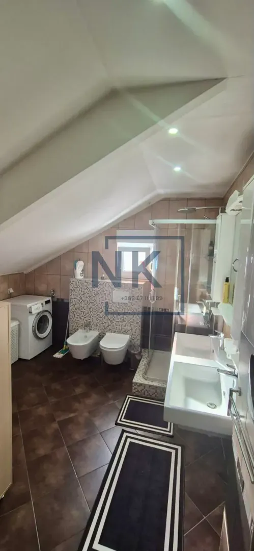 Bathroom with a shower cabin, double vanity, and washing machine in the attic.