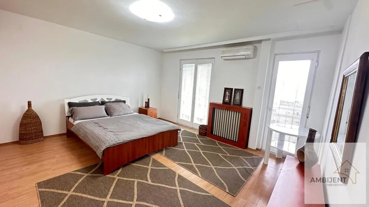 Spacious bedroom with a double bed, hardwood flooring, and access to the terrace.