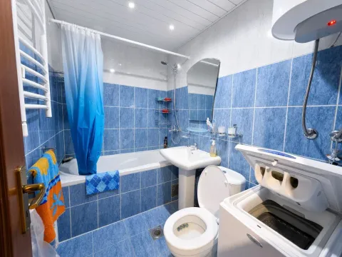 Kupatilo obloženo plavim pločicama sa kadom, umivaonikom, WC šoljom i veš mašinom. - image 17