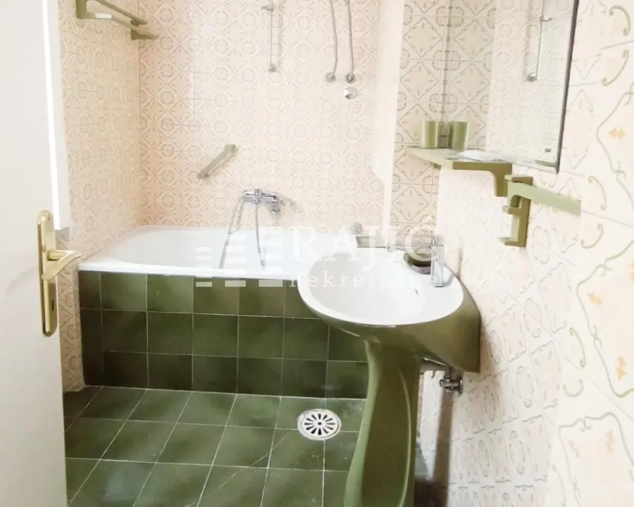 Manje kupatilo sa kadom, umivaonikom i retro pločicama.