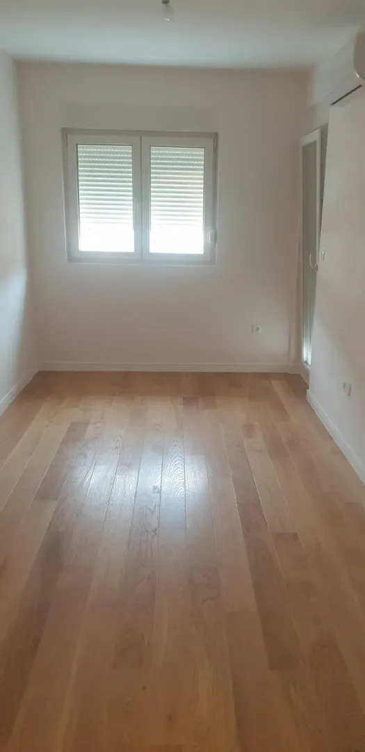 An empty room with light wooden flooring and white walls.