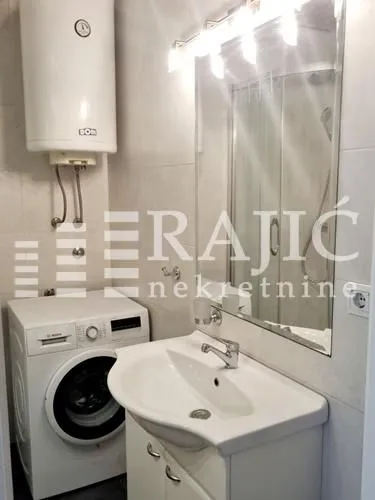 Small bathroom with a sink, washing machine, and water heater.