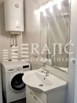 Small bathroom with a sink, washing machine, and water heater. - image 4
