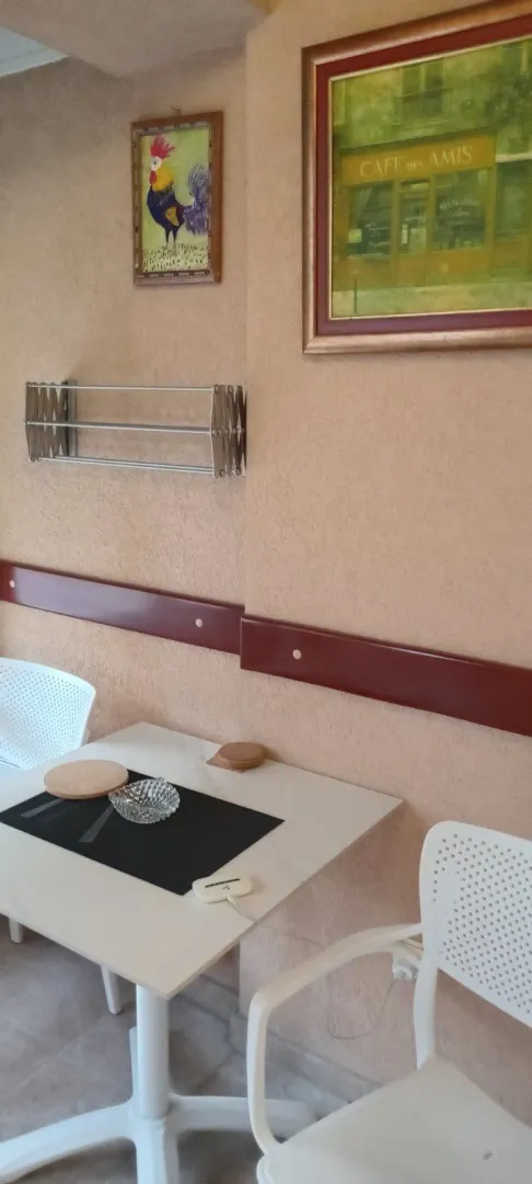 Manji sto sa stolicama na natkrivenoj terasi sa zidnim dekoracijama.