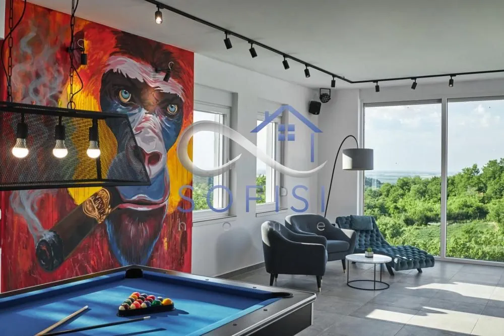 Living room with a pool table, large wall mural, and nature view.